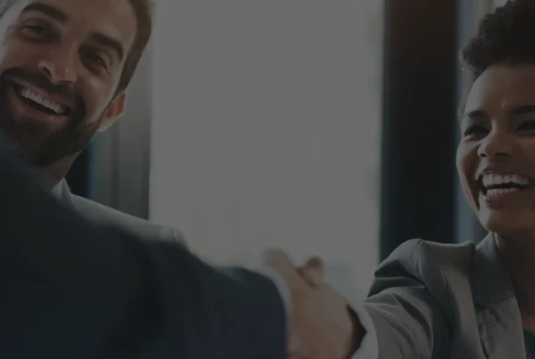Smiling business partners shaking hands in a bright office